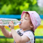 Rainwater marka su içen çocuk, yaz günü parkta serinliyor.