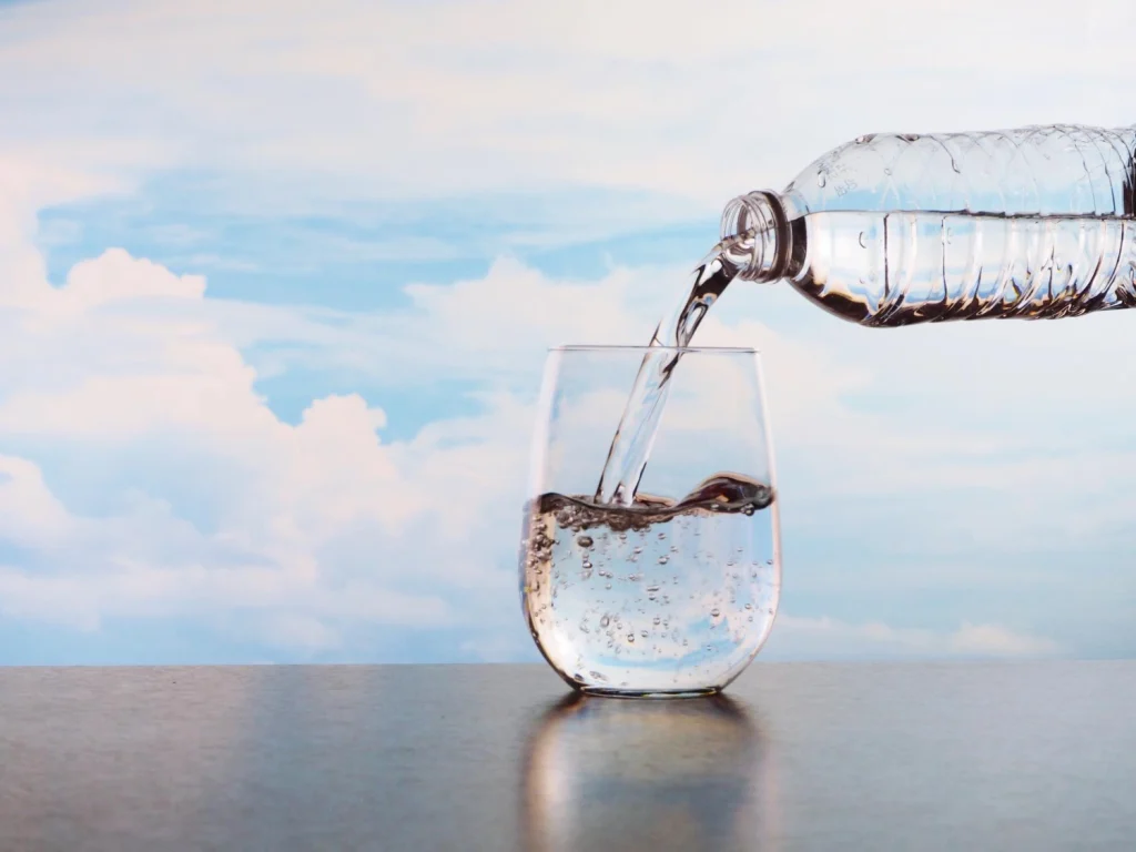 Pouring water from a Rainwater bottle into a glass, high quality natural drinking water.